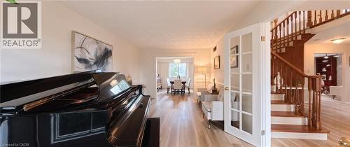 Wood-finish flooring, glass-paneled French doors, and an open staircase featuring a stained wood handrail and balusters - 488 Heather Hill Place, Waterloo, ON 
