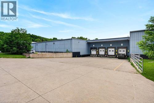 Industrial building exterior featuring four dock-high loading bays, a concrete loading apron, and metal siding construction - 47 Head Street, Hamilton, ON 