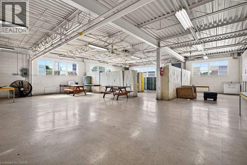 Industrial-style interior featuring high-clearance exposed truss ceilings, extensive tile flooring, white masonry block walls, and abundant natural light from multi-pane windows - 47 Head Street, Hamilton, ON 
