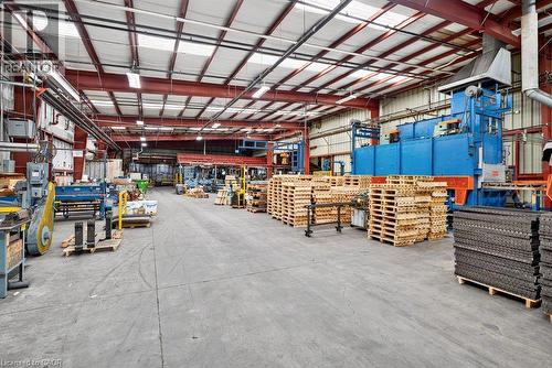 Industrial warehouse interior featuring exposed steel truss framing, concrete flooring, high-clearance ceilings, and overhead fluorescent lighting - 47 Head Street, Hamilton, ON 
