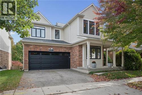 Two-story residence featuring a combination brick and horizontal siding exterior, a covered front porch with columns, and an attached two-car garage with black paneled doors - 83 Glazebrook Crescent, Cambridge, ON 