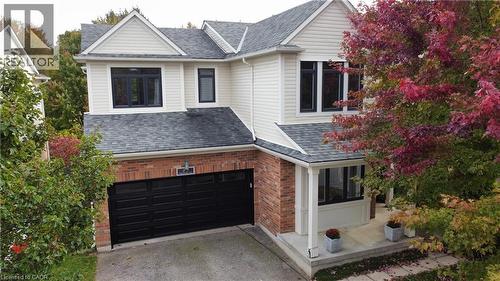 Two-story residence featuring a mixed-material exterior of light-toned siding and red brick, a multi-paneled garage door, architectural shingle roofing, and a covered front entry - 83 Glazebrook Crescent, Cambridge, ON 
