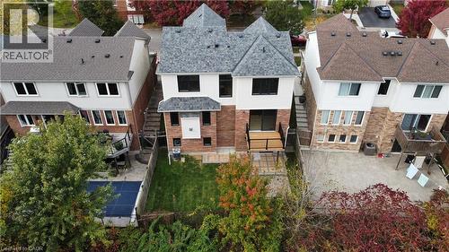 Rear elevation featuring a brick and siding facade, multi-pitched shingle roof, elevated wood deck, rear lawn, and privacy fencing - 83 Glazebrook Crescent, Cambridge, ON 