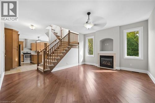 Open concept interior featuring wood-finish flooring, a built-in fireplace with recessed media niche, wooden staircase railing, and natural lighting from multiple windows - 83 Glazebrook Crescent, Cambridge, ON 