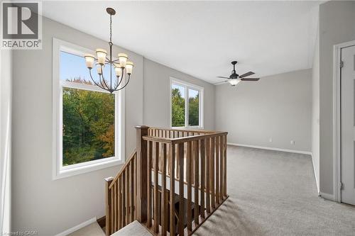 Open floor plan featuring wall-to-wall carpeting, wood-finish stair railings, a multi-arm chandelier, and a ceiling fan with integrated lighting - 83 Glazebrook Crescent, Cambridge, ON 