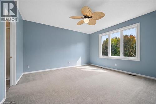 Spacious room featuring neutral carpeting, a triple-pane window, and a decorative palm-leaf style ceiling fan - 83 Glazebrook Crescent, Cambridge, ON 