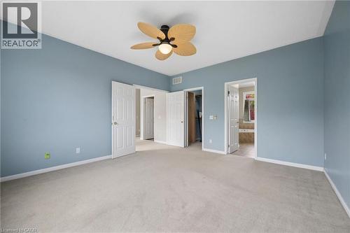 Spacious room featuring carpeting, a multi-blade ceiling fan, and white paneled doors - 83 Glazebrook Crescent, Cambridge, ON 
