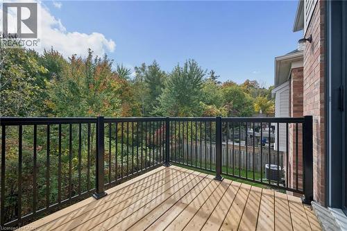 Elevated wood-plank deck featuring a black metal railing and exterior brick siding - 83 Glazebrook Crescent, Cambridge, ON 