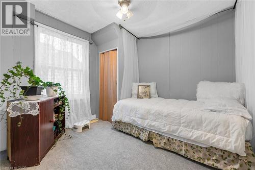 Room featuring neutral wall paneling, wall-to-wall carpeting, a multi-pane window, and a wooden bi-fold closet door - 143 Walter Avenue S, Hamilton, ON 