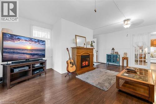Living area featuring wood-finish flooring, a built-in wood-surround fireplace, wainscoting, and a multi-pane glass-panel door - 143 Walter Avenue S, Hamilton, ON 