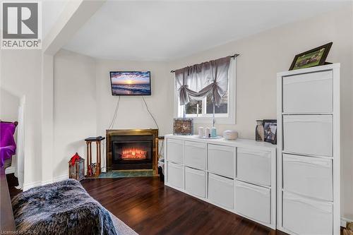 Fireplace with a metal surround and tile hearth, complemented by wood-finish flooring - 143 Walter Avenue S, Hamilton, ON 