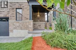 Exterior facade featuring multi-tonal brick and stone masonry, covered entryway with dark-finish support columns, and paver stone driveway - 