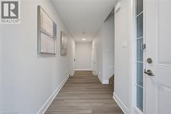 Hallway featuring wood-finish flooring, recessed lighting, and a white entry door with glass pane detailing - 