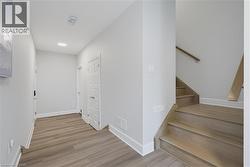 Interior foyer featuring wood-finish flooring, recessed lighting, and a staircase with wood-finish treads and a wall-mounted handrail - 