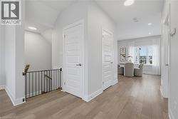 Hallway featuring wide-plank wood-finish flooring, recessed ceiling lighting, and solid-core five-panel interior doors with brushed nickel hardware - 