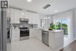 Kitchen featuring high-gloss white cabinetry, stainless steel appliances, stone-finish countertops, geometric tile backsplash, and oversized floor tiles - 