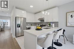 Kitchen featuring high-gloss white cabinetry, a center island with a stone-finish countertop, stainless steel appliances, linear tile backsplash, and recessed lighting - 