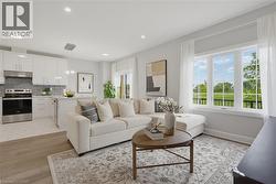 Open-concept kitchen featuring white shaker-style cabinetry, stainless steel appliances, and a tiled backsplash, paired with a main living area boasting wood-finish flooring and a large multi-pane bay - 