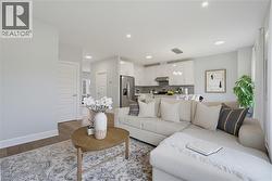 Open-concept interior featuring wood-finish flooring, recessed lighting, and kitchen cabinetry with a high-gloss finish - 