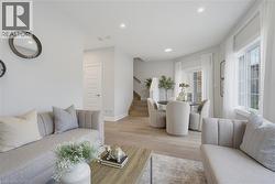 Open-concept interior featuring light wood-finish flooring, recessed lighting, grid-patterned windows, and a glass sliding door - 