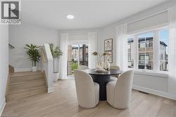 Wood-finish flooring, multi-pane window configuration, sliding glass door to exterior balcony, and staircase with wooden handrail - 