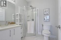 Corner shower stall with glass enclosure and handheld fixture, white vanity cabinet with stone-composite countertop, undermount sink, and tile flooring - 