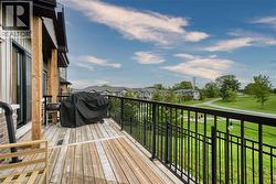 Outdoor deck featuring wood-finish decking, black metal railing, and wood support columns - 
