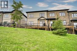 Multi-story exterior featuring a brick and vertical siding facade, elevated wooden decks, and black metal railings - 