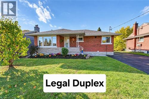 Single-story brick exterior featuring a stone-clad facade, asphalt shingle roof, covered front porch, and paved driveway - 46 Traynor Avenue, Kitchener, ON 