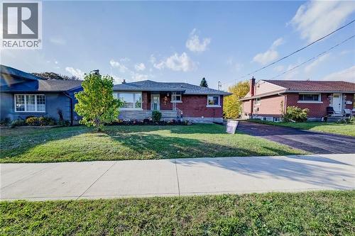 Brick exterior facade featuring a covered front porch, stone accents, asphalt driveway, and a shingled roof - 46 Traynor Avenue, Kitchener, ON 