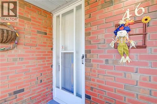 Red brick exterior facade featuring a white storm door with glass paneling - 46 Traynor Avenue, Kitchener, ON 