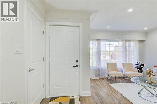 Entryway featuring a white paneled door with matte black hardware, wood-finish flooring, recessed ceiling lighting, and a multi-pane window - 46 Traynor Avenue, Kitchener, ON 