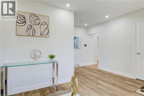 Neutral-toned interior featuring wood-finish flooring, recessed lighting, and a solid-core panel door - 46 Traynor Avenue, Kitchener, ON 