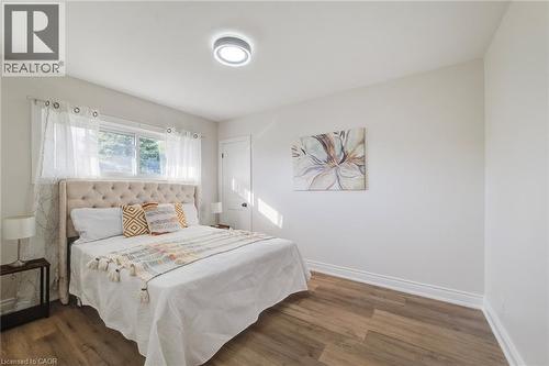 Neutral-toned interior featuring wood-finish flooring, a horizontal sliding window, and a circular LED flush-mount ceiling light - 46 Traynor Avenue, Kitchener, ON 