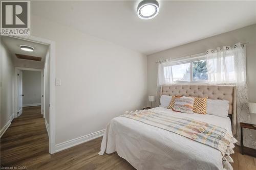 Neutral-toned interior featuring wood-finish flooring, dual flush-mount ceiling light fixtures, and a horizontal sliding window - 46 Traynor Avenue, Kitchener, ON 