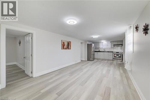 Open-concept space featuring wood-finish flooring, recessed lighting, and kitchen cabinetry paired with stainless steel appliances - 46 Traynor Avenue, Kitchener, ON 