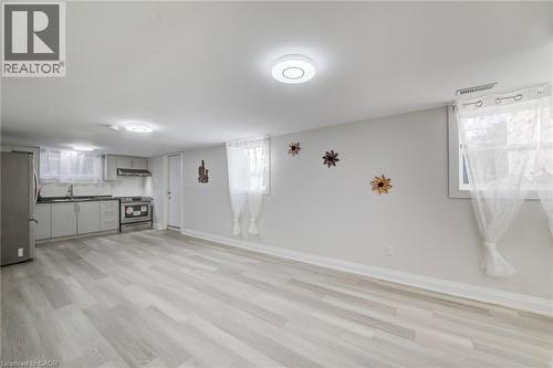 Open-concept room featuring wood-finish flooring, recessed lighting, and a kitchenette equipped with stainless steel appliances, light-toned cabinetry, and a tile backsplash - 46 Traynor Avenue, Kitchener, ON 