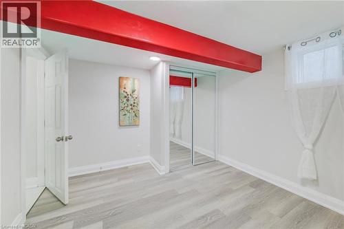 Room featuring wood-finish flooring, sliding mirror-door closet, recessed ceiling lighting, and a window with natural light - 46 Traynor Avenue, Kitchener, ON 