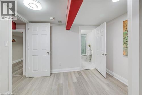 Interior area featuring light-toned wood-finish flooring, white six-panel doors, neutral wall paint, and exposed structural support beam - 46 Traynor Avenue, Kitchener, ON 
