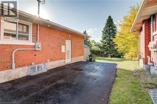Brick exterior featuring a private asphalt driveway, concrete foundation, and window wells - 46 Traynor Avenue, Kitchener, ON 