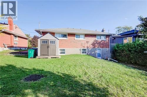 Rear exterior featuring red brick siding, a hip roof, multi-pane windows, and a level lawn area - 46 Traynor Avenue, Kitchener, ON 