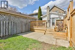Rear exterior featuring a wooden deck with railing, concrete patio, a built-in wood planter, and a brick chimney - 