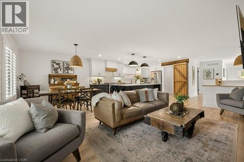 Open-concept floor plan featuring wood-finish flooring, kitchen island with contrasting cabinetry, sliding barn door, and pendant lighting - 361 Lee Circle, Waterloo, ON 