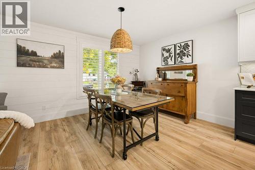 Dining area featuring horizontal shiplap wall paneling, wood-finish flooring, a woven pendant light fixture, and plantation shutters - 361 Lee Circle, Waterloo, ON 