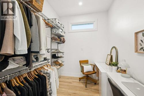 Walk-in storage space featuring wood-finish flooring, multi-level wire shelving, a horizontal window, and built-in white desk cabinetry - 361 Lee Circle, Waterloo, ON 