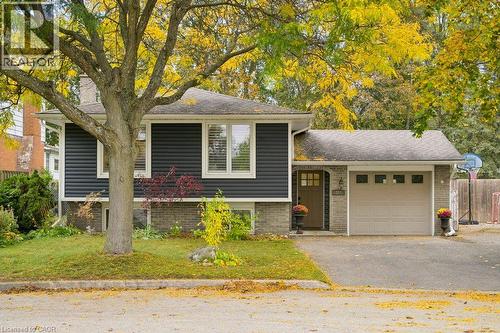 Split-level exterior featuring dark horizontal siding, brick masonry lower cladding, an attached garage, and a recessed entryway with a multi-pane front door - 361 Lee Circle, Waterloo, ON 