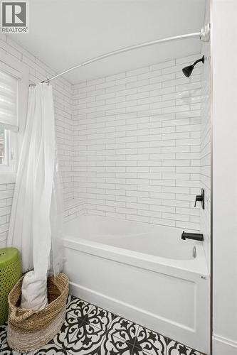 Bathtub and shower surround featuring white subway tile, matte black plumbing fixtures, and patterned decorative floor tile - 361 Lee Circle, Waterloo, ON 