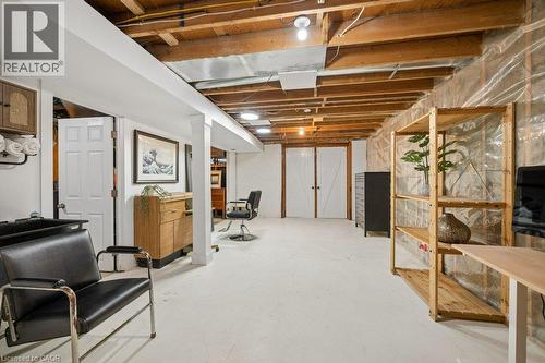 Open-concept lower level featuring exposed wood ceiling joists, painted concrete floors, white structural columns, and double-door entryway - 361 Lee Circle, Waterloo, ON 