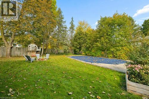 Expansive backyard featuring a lawn, mature trees, an in-ground pool with a safety cover, and perimeter wood fencing - 361 Lee Circle, Waterloo, ON 