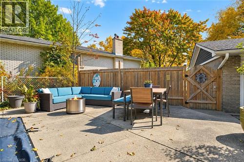 Concrete patio featuring a perimeter wood privacy fence, a custom wood gate with metal hardware, and brick exterior walls - 361 Lee Circle, Waterloo, ON 